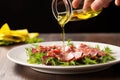 hand drizzling olive oil over a salami salad