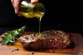 hand drizzling olive oil over a seasoned ribeye steak