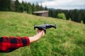 Hand with a drone on a background of mountain views with a meadow and coniferous forest. The pilot launches the drone from his Royalty Free Stock Photo