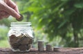 Hand drop a coin in glass jar with money coin stack growing for Royalty Free Stock Photo