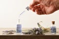 Hand with dropper filling bottle with lavender essence and plant