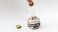 Hand dropping coin into Home deposit jar Royalty Free Stock Photo