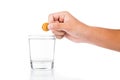 Hand dropping effervescent vitamin C tablet into glass of water