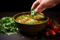 hand dropping fresh cilantro into a bowl of chicken tortilla soup