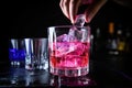 hand dropping ice cubes into a vibrant club soda drink