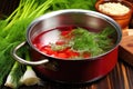 hand drops fresh dill sprigs into simmering borscht