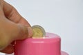 Hand drops Thai coin in pink piggy bank