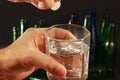 Hand with an effervescent pill from hangover over glass of water on a dark background. Royalty Free Stock Photo