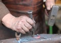 Hand elder blacksmith who uses an iron awl over a large anvil