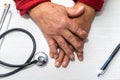 Hand of elderly man with osteoarthritis at doctor`s office on white table Royalty Free Stock Photo