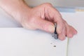 The hand of an elderly man sets the fastener during the assembly of furniture. Close-up. Selective focus Royalty Free Stock Photo