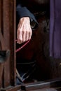 Hand of an elderly priest sitting in a confession box in a Catholic church in Italy. The priest is holding rosary beads.