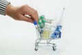 Hand of an elderly man moves a metal shopping cart with medicines on a white background Royalty Free Stock Photo