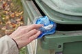 The hand of an elderly woman throws a crumpled, dirty plastic ba