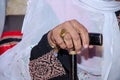 Hand of an elderly woman in traditional Bedouin clothing with embroidery based on a stick for walking