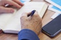 The hand of an elderly woman writing with a fountain pen in a notebook or diary. Memories or a will. Selective focus. No face Royalty Free Stock Photo