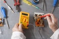 Hand of electrician with multimeter probe at electrical switchgear cabinet. Engineering tools