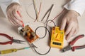 Hand of electrician with multimeter probe at electrical switchgear cabinet. Engineering tools