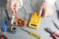 Hand of electrician with multimeter probe at electrical switchgear cabinet. Engineering tools