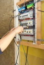 Hand of an electrician with screwdriver at an electrical switchgear cabinet.