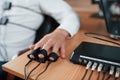 Hand with electrodes on fingers is on the table. Suspicious man passes lie detector in the office. Asking questions