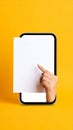 Hand emerging from smartphone screen holding blank white paper with finger pointing Royalty Free Stock Photo