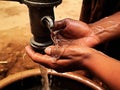 A hand emerging through a spout of a water pump and cupping the water to wet the face.. AI generation