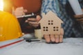 Hand of engineer and architect showing house model and working on blueprint on desk Royalty Free Stock Photo