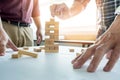 Hand of engineer playing a blocks wood tower game & x28;jenga& x29; on blu Royalty Free Stock Photo