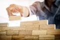 Hand of engineer playing a blocks wood tower game & x28;jenga& x29; on blu Royalty Free Stock Photo