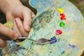 The hand of a European artist holds a mastekhin smeared in oil paint and a palette against the background of a green lawn. Blurred Royalty Free Stock Photo