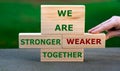 Hand exchanges a wooden brick and changes the expression `we are weaker together` to `we are stronger together`. Royalty Free Stock Photo