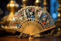 a hand fan decorated with traditional asian motifs, an electric fan in the soft focus background