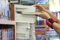 Hand female picking book from bookshelf in the library room