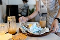 Hand of female waitress holding a tray with scraps of food,leftover food,dirty dishes,tissues and used protective face masks left