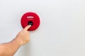 Hand with finger pressing red fire alarm on the wall Royalty Free Stock Photo