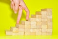 A hand finger walk on stacked wooden block like stairs. Business development and growth concept