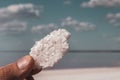 Hand holding salt crystal on salty pink lake