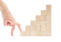 Hand fingers start climbing the stairs made of wooden toy blocks isolated on white background. Royalty Free Stock Photo