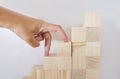 Hand fingers start climbing the stairs made of wooden toy blocks isolated on white background. First step on the career ladder con Royalty Free Stock Photo