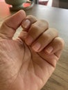 A hand and fingers of a woman and brown wood tabletop in the background.