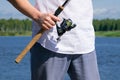 The hand of the fisherman holding the rod in the open air, in front of a white shirt Royalty Free Stock Photo