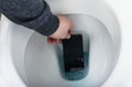 Hand fishing out the smartphone from the toilet water