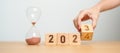 hand flipping block 2023 to 2024 text with hourglass on table. Resolution, time, plan, goal, motivation, reboot, countdown and