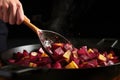 hand flipping roasted beets on a skillet with a spatula