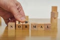 Hand flipping wooden block cubes for new normal wording. Adapting to new life or business post-lockdown after coronavirus pandemic