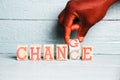 A hand flips a wooden cube with the words change into the word chance