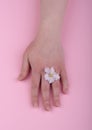 Hand with flower violets on a pink background. Skin care concept