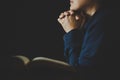 Hand folded in prayer to god on Holy Bible book in church concept for faith, spirituality and religion, woman person praying on