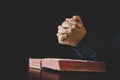 Hand folded in prayer to god on Holy Bible book in church concept for faith, spirituality and religion, woman person praying on